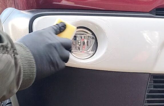スポンジで白いバンパーの擦り傷を磨いている様子